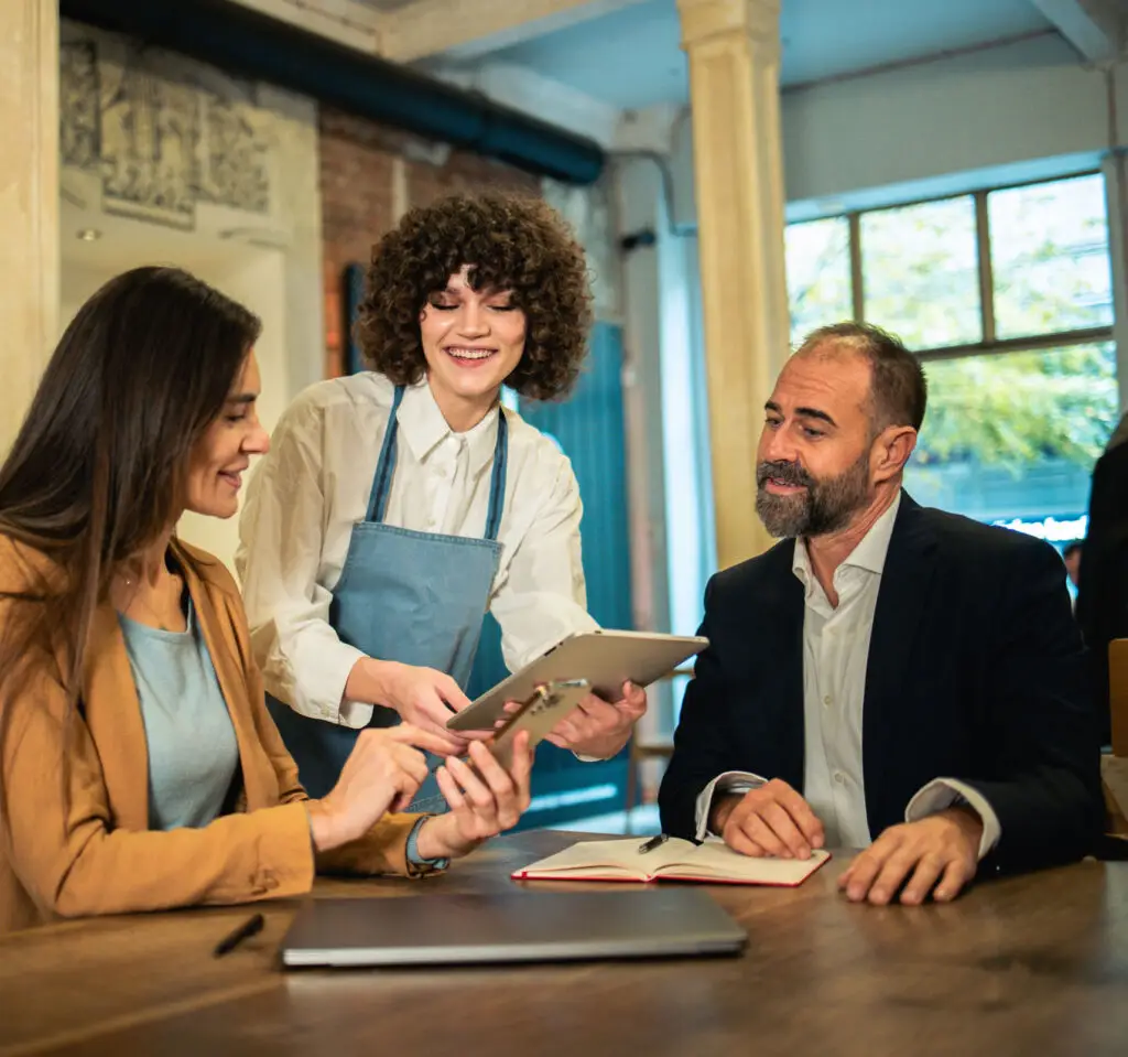 Two business partners having a business meeting at the restaurant and ordering their meal from the waitress